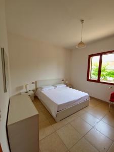 a bedroom with a white bed and a window at Aglaia in Torre Lapillo