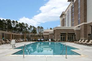 une piscine dans un hôtel avec des chaises et un bâtiment dans l'établissement Hilton Garden Inn Summerville, Sc, à Summerville