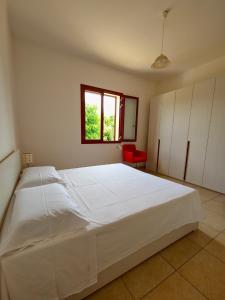 a large white bed in a bedroom with a red chair at Aglaia in Torre Lapillo