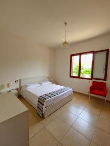 a bedroom with a large bed and a red chair at Aglaia in Torre Lapillo