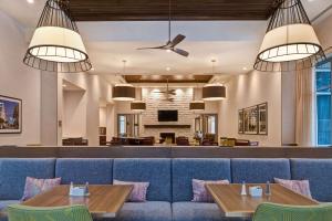 a dining room with a blue couch and tables at Homewood Suites By Hilton Summerville in Summerville