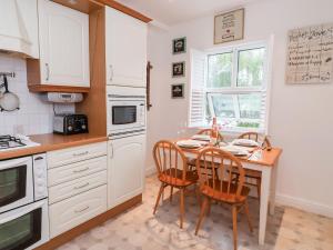 a kitchen with a table and two chairs and a kitchen with white cabinets at 1 Cockerill Fold in Beverley