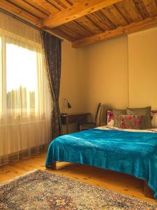 ein Schlafzimmer mit einem Bett mit einer blauen Decke und einem Fenster in der Unterkunft House in Druskininkai Oldtown in Druskininkai