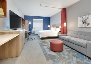 ユーレスにあるHome2 Suites By Hilton Euless Dfw West, Txのベッドとリビングルームが備わるホテルルームです。
