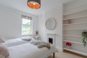 a white bedroom with two beds and a mirror at Otley House in Cheltenham