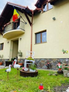 a house with a balcony and two birds in the yard at Casa Raisa & Maria in Ocna Sibiului
