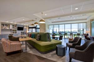 un vestíbulo con un sofá verde, mesas y sillas en Home2 Suites By Hilton Lewisville Dallas, en Lewisville