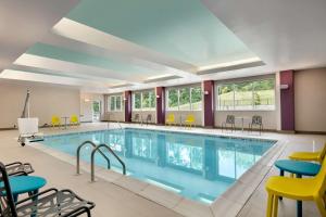 una piscina en una habitación de hotel con sillas y mesas en Tru By Hilton Easton, en Easton