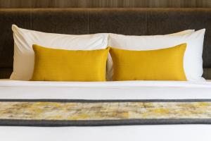 Bandalo Boutique Hotel في شاطيء باتونغ: وسادتين على سرير مع وسادتين صفراء