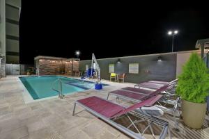 einen Pool mit Liegestühlen und einen Swimmingpool in der Nacht in der Unterkunft Home2 Suites By Hilton Buckeye Phoenix in Buckeye