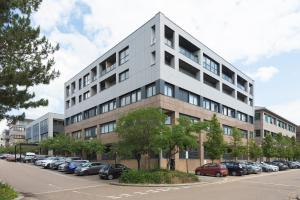 un gran edificio gris con coches estacionados en un estacionamiento en Deluxe 2 bed, 2 bathroom Milton Keynes apartment within walking distance to train station and City centre. en Milton Keynes