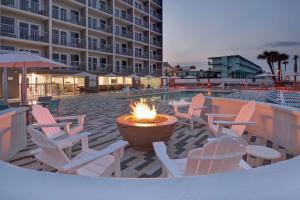 une terrasse avec des chaises et un foyer extérieur en face de l'hôtel dans l'établissement Home2 Suites Ormond Beach Oceanfront, FL, à Ormond Beach