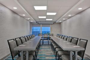 une salle de conférence avec de longues tables et chaises dans l'établissement Home2 Suites Ormond Beach Oceanfront, FL, à Ormond Beach