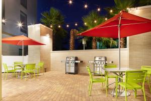 a patio with green chairs and tables and red umbrellas at Home2 Suites By Hilton Stuart in Stuart