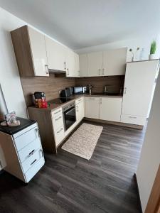 a kitchen with white cabinets and a wooden floor at Ferienwohnung Schennach in Obsteig