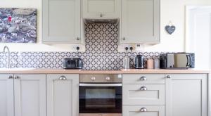 una cucina con mobili bianchi e un piano di lavoro di Dove Cottage a Sawrey