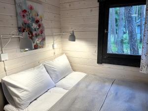 białe łóżko w pokoju z oknem w obiekcie Domki - Sosnowy Las w Pobierowie