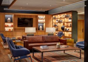 sala de estar con sofá marrón y sillas azules en Canopy By Hilton Baltimore Harbor Point - Newly Built en Baltimore