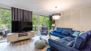 sala de estar con sofá azul y TV de pantalla plana en Apartamenty Sun & Snow Łukęcin, en Łukęcin