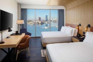 a hotel room with two beds and a desk and a window at Canopy By Hilton Baltimore Harbor Point - Newly Built in Baltimore