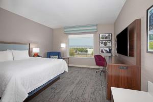 Hampton Inn & Suites Gilroy, Ca في جيلروي: غرفة فندقية بسرير وتلفزيون بشاشة مسطحة