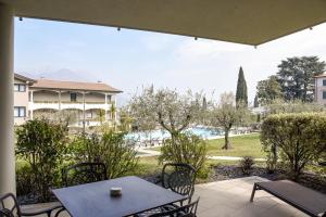 a patio with a table and chairs and a view of a pool at Bella Hotel & Restaurant with private dock for mooring boats in San Felice del Benaco