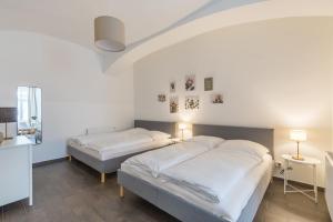 two beds in a bedroom with white walls and wood floors at Cozy Heaven in the lovely 2nd district of Vienna in Vienna