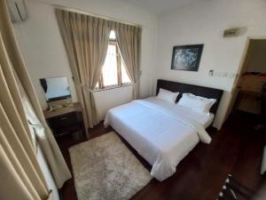 una camera da letto con un grande letto bianco e una finestra di Semi detached At Tabuan Jaya,13BR By Natol Homestay-London a Kuching