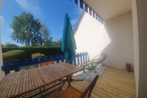 een patio met een tafel en een parasol bij Appartement rez de jardin proche du centre ville de sarzeau in Sarzeau
