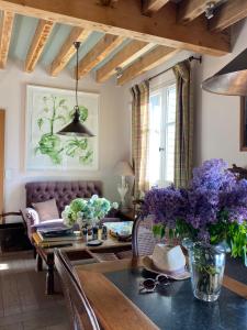 Lodge Saint-Hymer في Saint-Hymer: غرفة معيشة مع طاولة مع زهور أرجوانية عليها