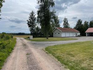 a dirt road next to a house and a tree at Katthagen in Skara