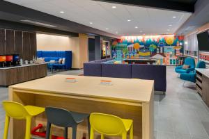 una zona de espera para niños con sillas amarillas y azules en Tru By Hilton Spartanburg, en Spartanburg