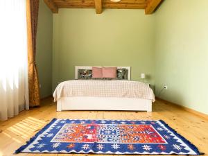 ein Schlafzimmer mit einem Bett und einem Teppich auf einem Holzboden in der Unterkunft House in Druskininkai Oldtown in Druskininkai