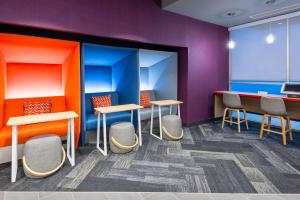 una sala de espera de colores brillantes con mesas y sillas en Tru By Hilton Spartanburg, en Spartanburg