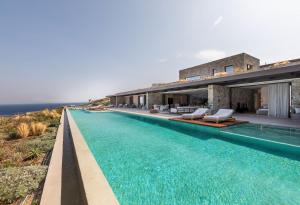 a house with a swimming pool next to the ocean at Untold Mykonos in Mikonos