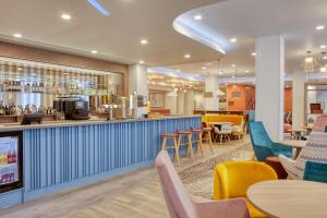 un restaurante con bar, mesas y sillas en Hampton By Hilton Manchester Northern Quarter, en Mánchester