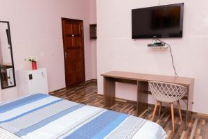 a bedroom with a desk and a television on a wall at Guajará Palace Hotel in Porto Velho