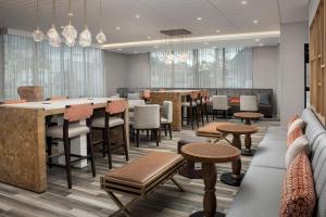 a restaurant with a bar and tables and chairs at Hampton Inn Boston Logan Airport Chelsea in Chelsea
