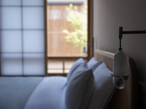 a bedroom with a bed with a lamp and a window at tamao-たま靑- in Kyoto