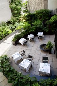 patio z białymi stołami, krzesłami i roślinami w obiekcie Atocha Hotel Madrid, Tapestry Collection by Hilton w Madrycie