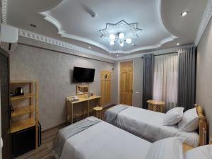 a hotel room with two beds and a television at Hanifa Boutique in Samarkand