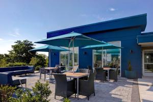 un patio con mesas y sillas y sombrillas azules en Hampton Inn & Suites Deptford, Nj, en Deptford