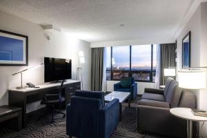カルガリーにあるDoubleTree by Hilton Calgary Northのデスクとリビングルームが備わるホテルルームです。