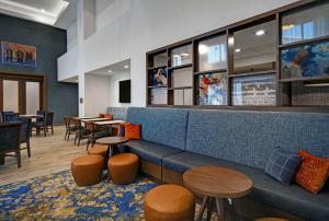 a restaurant with a blue couch and tables and chairs at Hampton Inn Midland South, Tx in Midland