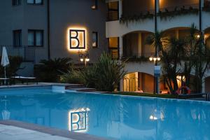 a hotel with a swimming pool in front of a building at Bella Hotel & Restaurant with private dock for mooring boats in San Felice del Benaco