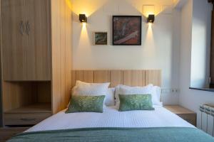 um quarto com uma cama grande e 2 almofadas verdes em alojamiento cuatro estaciones em La Pola de Gordón