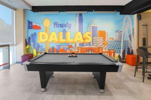 un tavolo da biliardo in una stanza con un felice murale di Dallas di Tru By Hilton Dallas Market Center a Dallas