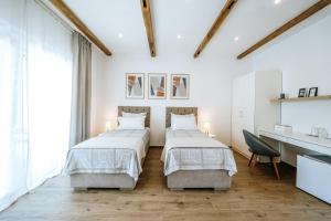 two beds in a bedroom with white walls and wooden floors at Old Town Zagreb Airport in Velika Gorica
