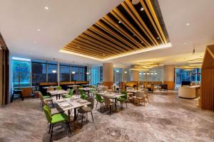 un ristorante con tavoli, sedie e finestre di Hilton Garden Inn Nantong Xinghu a Nantong
