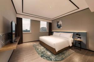 una camera con letto bianco e TV di Hilton Garden Inn Nantong Xinghu a Nantong